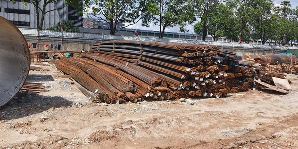 Stacks of rusted steel rods at a construction site on a sunny day.
